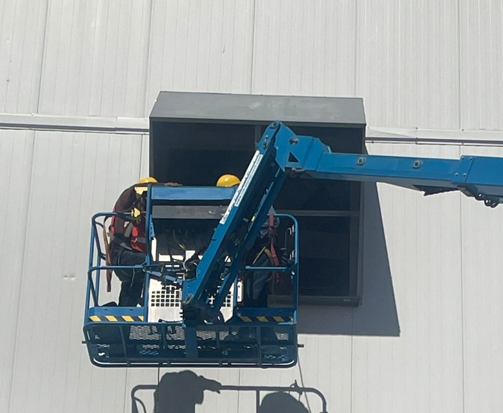 Personal en plataforma elevadora durante montaje de cubierta en pared
